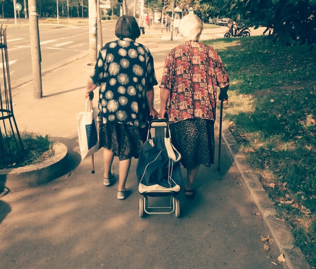 Zdjęcie z tyłu widok starszych kobiet idących po drodze w parku