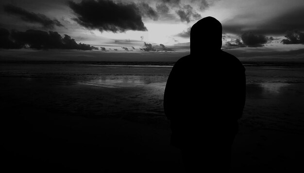 Zdjęcie z tyłu widok sylwetki osoby stojącej na plaży na tle nieba