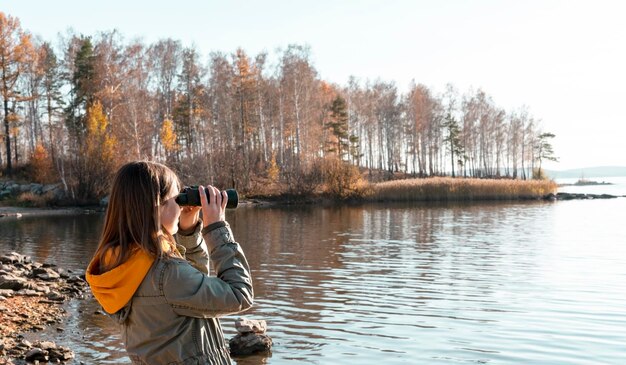 Zdjęcie z tyłu zdjęcie kobiety fotografującej jezioro na tle nieba