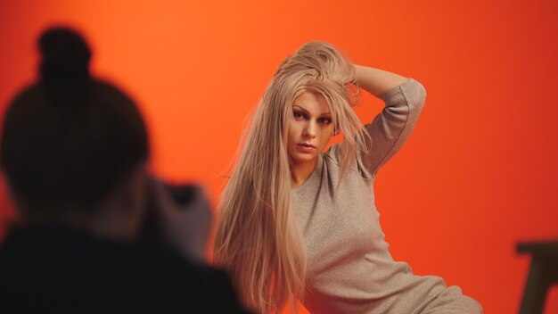 Za kulisami: blond modelka pozuje dla fotografa w czerwonym studio, zbliżenie