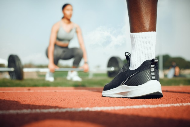 Zaangażowany w fitness Zbliżenie nierozpoznawalnego sportowca stojącego na zewnątrz, podczas gdy kobieta ćwiczy z ciężarami w tle
