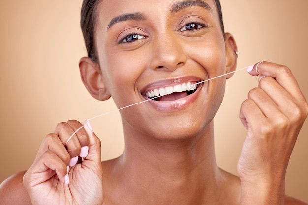 Ząb kobiety i nić dentystyczna w portrecie studyjnym z czyszczeniem uśmiechu lub samoopieką na brązowym tle Modelka dziewczyny i szczęśliwa z powodu sznurka produktu dentystycznego lub wybielania zębów w kosmetykach uroda lub zdrowie