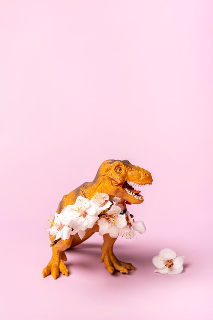 Zabawka dinozaur Tyrannosaurus trzymający kwiat moreli w łapach