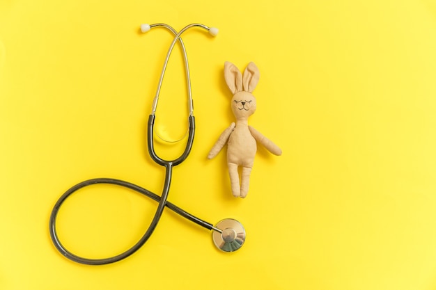 Zabawka królik i stetoskop sprzęt medycyny na białym tle na żółtym tle