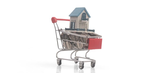 Zabawka wózek na zakupy z modelem domu na monetach i koncepcji dostawy. Trend społeczeństwa konsumenckiego