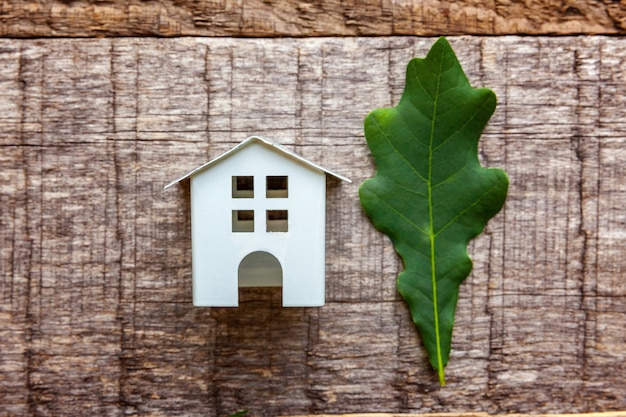 Zabawkarski Dom i zielony dębowy liść na drewnianym tle