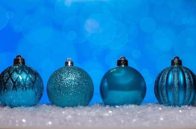 Zabawki choinkowe w kolorze niebieskim stojące na śniegu.