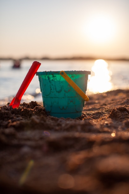 Zabawki Dla Dzieci Do Zabawy Na Piasku. Plastikowe Wiadro I Grabie Na Plaży O Zachodzie Słońca. Pojęcie Lata, Wakacji Rodzinnych I Wakacji.