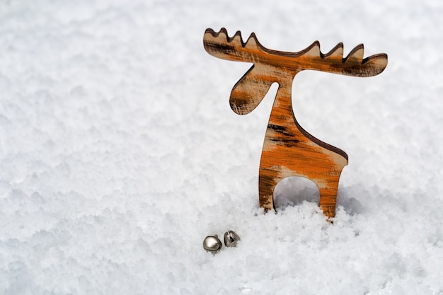 Zdjęcie zabawki drewniane mały jeleń z dzwoneczkami na zaśnieżonej powierzchni