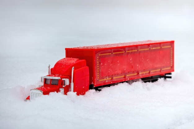 Zabawkowa czerwona ciężarówka przynosi prezenty sylwestrowe i świąteczne Zbliżają się ferie zimowe jeżdżą w prawdziwych zaspach