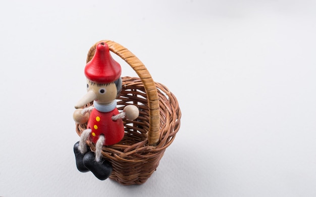 Zabawkowa figurka Pinokia siedząca w koszu