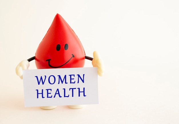 Zabawkowa kropla krwi zawiera białą kartkę z napisem WOMEN HEALTH.