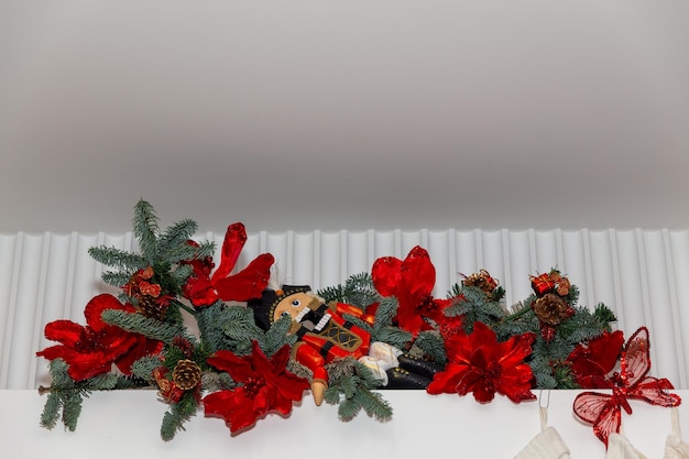 Zabawkowy dziadek do orzechów wiszący w świątecznej kompozycji na białej ścianie