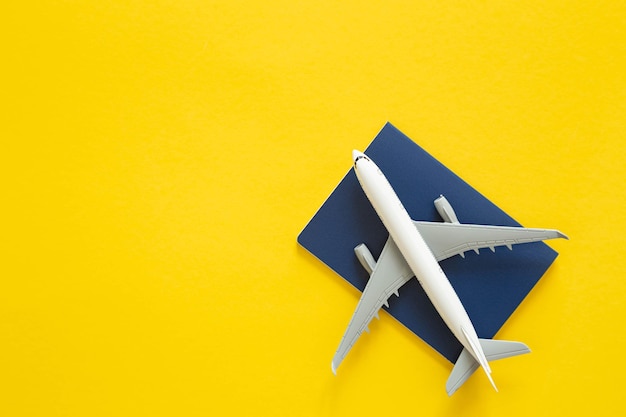 Zabawkowy samolot pasażerski i paszport na żółtym tle z góry