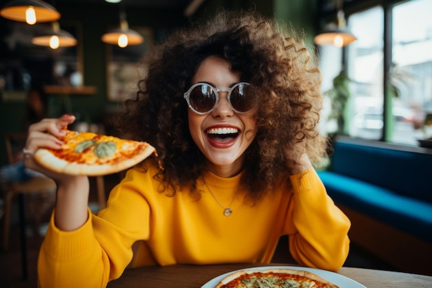 Zdjęcie zabawna brunetka w żółtym swetrze jedząca pizzę w restauracji.