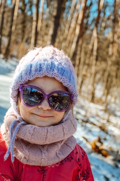 Zabawna dziewczyna w okularach przeciwsłonecznych i dzierżonym kapeluszu w zimie
