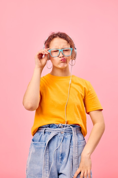 Zabawna dziewczyna żółta koszulka słuchawki rozrywka muzyka zabawa różowe tło niezmienione