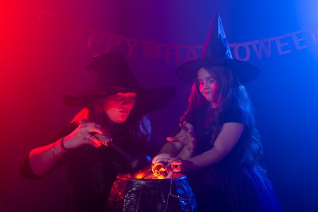 Zabawna dziewczynka i kobieta w strojach czarownic na Halloween z dyniowym Jackiem i psem