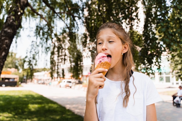 Zdjęcie zabawna dziewczynka jedząca lody w kubku waflowym kreatywna reklama na stoisko z lodami i sklep