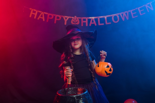 Zabawna dziewczynka w stroju wiedźmy na halloween z dyniowym Jackiem