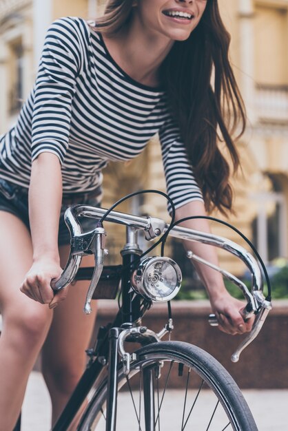 Zabawna jazda. Zbliżenie pięknej młodej kobiety jadącej na rowerze wzdłuż ulicy i uśmiechniętej