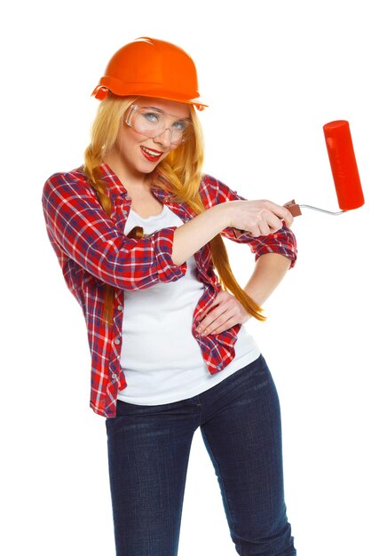 Zdjęcie zabawna kobieta konstruktorka w hełmie z wałkiem w ręku jest izolowana na białym tle