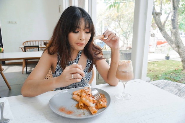 Zabawna młoda azjatycka kobieta jedząca smaczny makaron w kawiarni