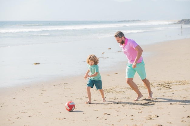 Zabawna rodzina tatusia i chłopca grającego w piłkę na rodzicielstwie na plaży