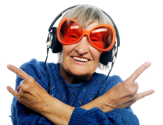 Zabawna starsza pani słuchająca muzyki i pokazująca kciuki do góry izolowany na białym