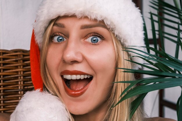 Zdjęcie zabawna szeroko uśmiechnięta blondynka ubrana w santa hat patrząca w kamerę z zaskoczonymi oczami dziewczyna celeb