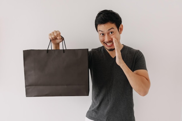 Zabawna twarz azjatyckiego mężczyzny, który kupuje fajny produkt w torbie