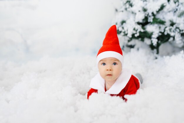 Zabawne dziecko w małym stroju Świętego Mikołaja na sztucznym śniegu