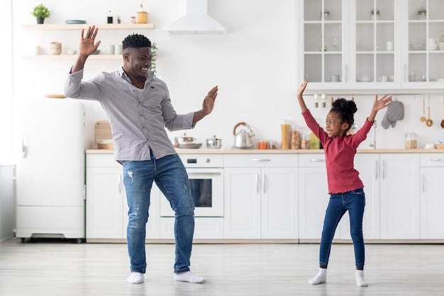 Zabawny afroamerykański ojciec i córka tańczą w kuchni