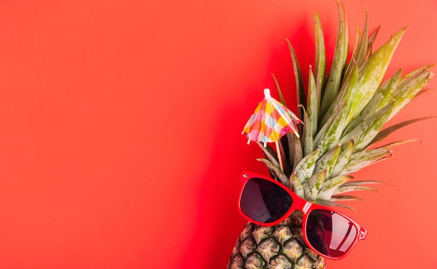 zabawny ananas nosi czerwone okulary przeciwsłoneczne, leży płasko