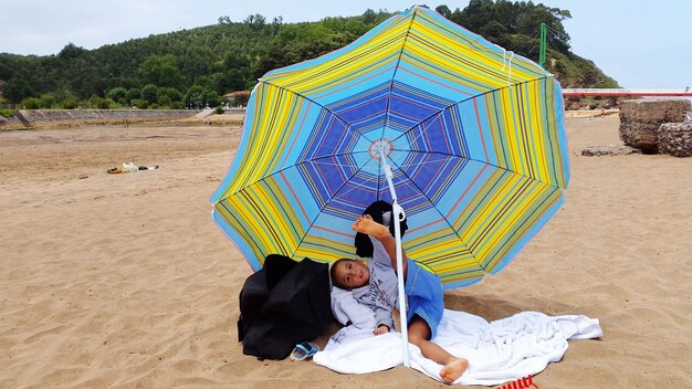 Zabawny chłopiec przy parasolu na plaży