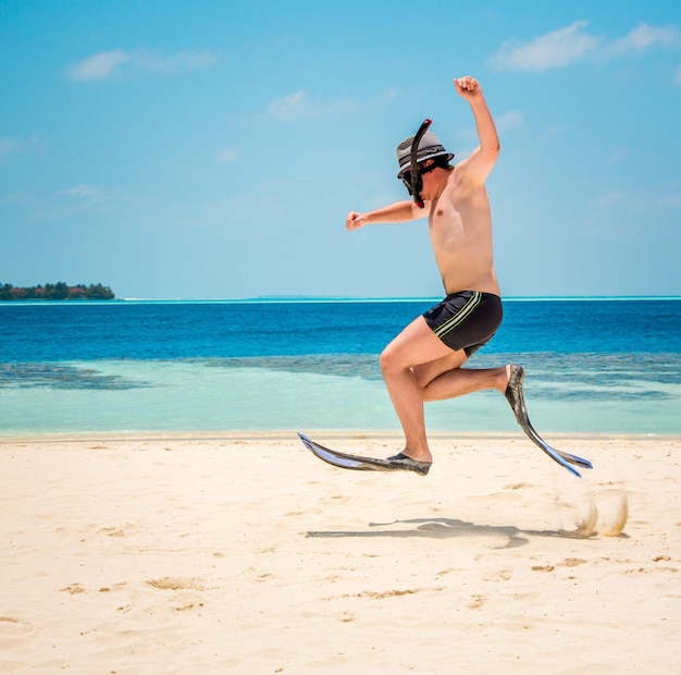 Zabawny człowiek skaczący w płetwy i maskę. Wakacyjne wakacje na tropikalnej plaży na Malediwach.