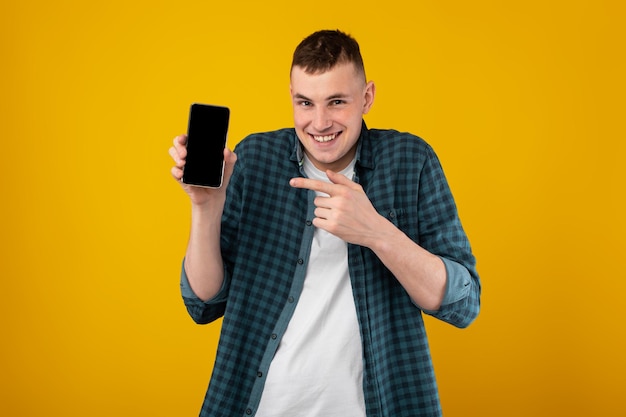 Zabawny Facet Pokazujący Telefon Wskazujący Palcem Na żółtym Tle Ekranu