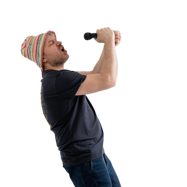Zabawny nieogolony mężczyzna 40 lat w jasnym kapeluszu trzyma mikrofon w dłoniach izolowany na białym tle