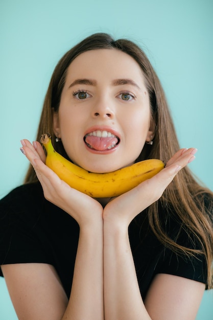 Zabawny portret młodej kobiety z bananem na kolorowym tle