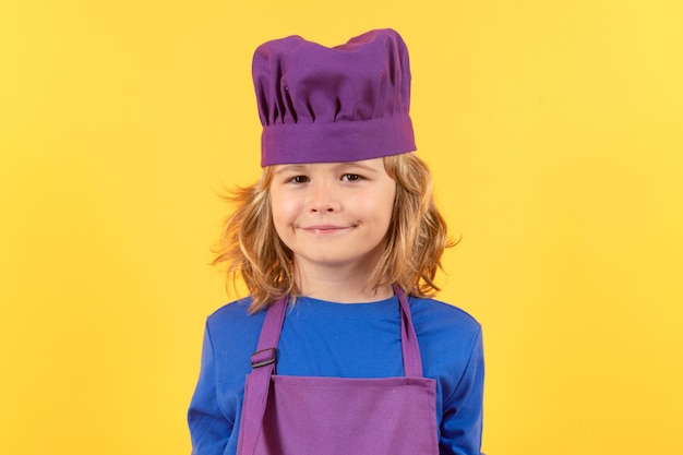 Zabawny portret szefa kuchni kucharza Gotowanie dzieci Chłopiec szefa kuchni w postaci kucharza Chłopiec z fartuchem i kapeluszem szefa kuchni przygotowujący zdrowy posiłek w kuchni Proces gotowania