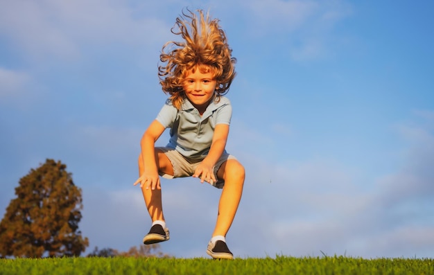 Zabawny rudy chłopiec bawiący się na zielonej trawie w parku szczęśliwe dzieciństwo dzieci aktywny styl życia na świeżym powietrzu