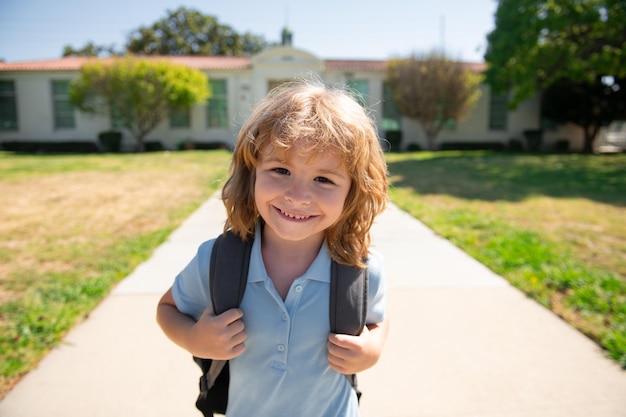 Zabawny szczęśliwy chłopiec szkolny wraca do szkoły słodkie dziecko z plecakiem biega i idzie do szkoły