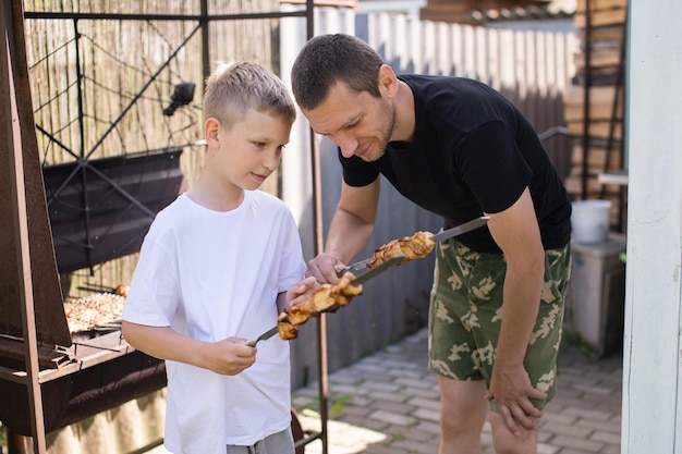 Zabawny tata i syn próbują grillowanego mięsa