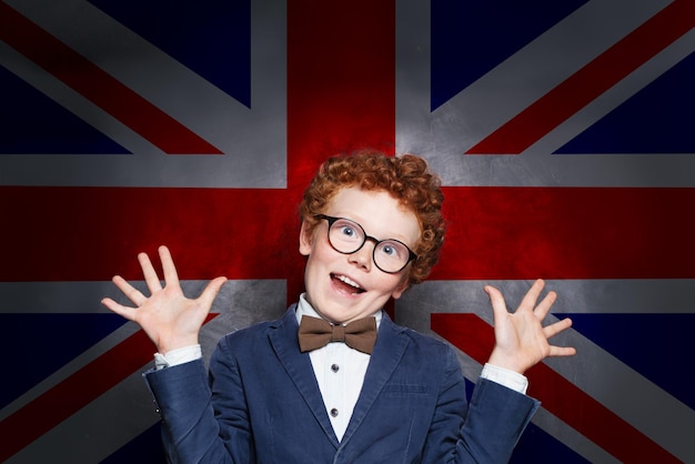 Zabawny złośliwy chłopiec uczeń na tle flagi Wielkiej Brytanii Naucz się angielskiej koncepcji