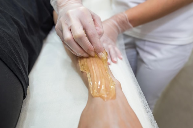 Zdjęcie zabieg depilacji pastą cukrową shugaring kosmetolog nakłada pastę cukrową na dłoń młodej kobietydepilacja kobiecych dłoni w gabinecie kosmetycznym