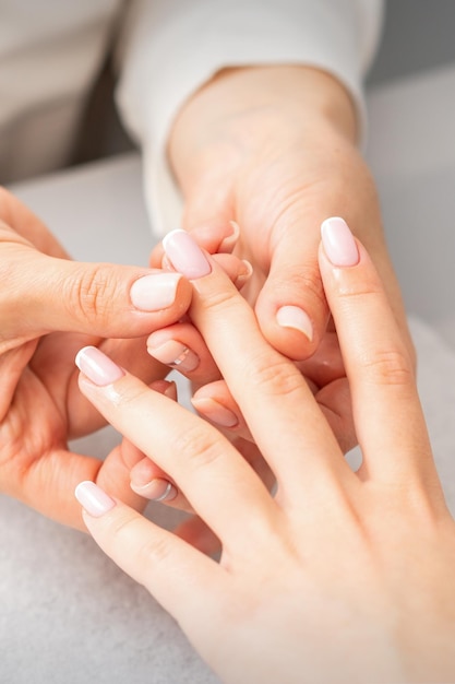 Zabieg manicure w spa. Dłoń kobiety podczas masażu palca z olejkiem w salonie paznokci.