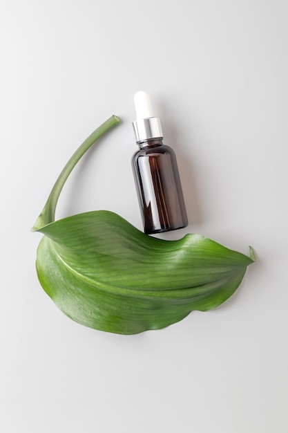 Zabiegi kosmetyczne pielęgnacja skóry i balsam kosmetyczny serum lub makieta oleju opakowanie produktu na szarym tle Nowoczesna prezentacja produktu z zielonymi liśćmi
