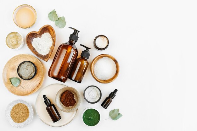 Zdjęcie zabiegi kosmetyczne składniki do robienia domowej maski kosmetycznej do pielęgnacji skóry. różne miski z gliną, śmietaną, olejkiem eterycznym i naturalnymi składnikami na białym tle stołu. ekologiczne produkty kosmetyczne spa
