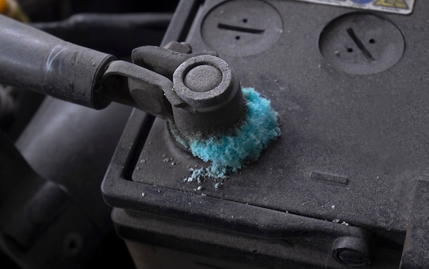 Zdjęcie zabrudzony zacisk akumulatora samochodu z niebieskimi krystalicznymi osadami.