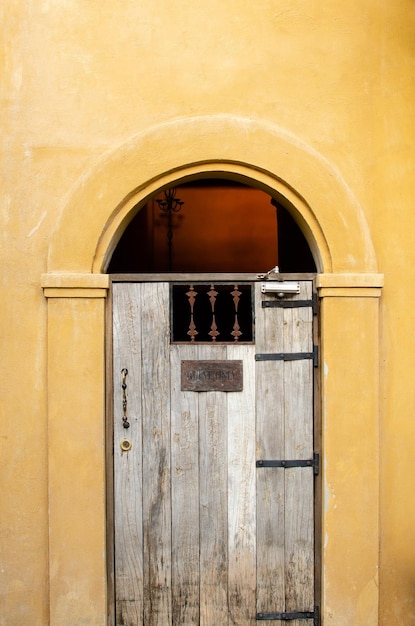 Zabytkowe drewniane drzwi na żółtym tle pastelowej ściany
